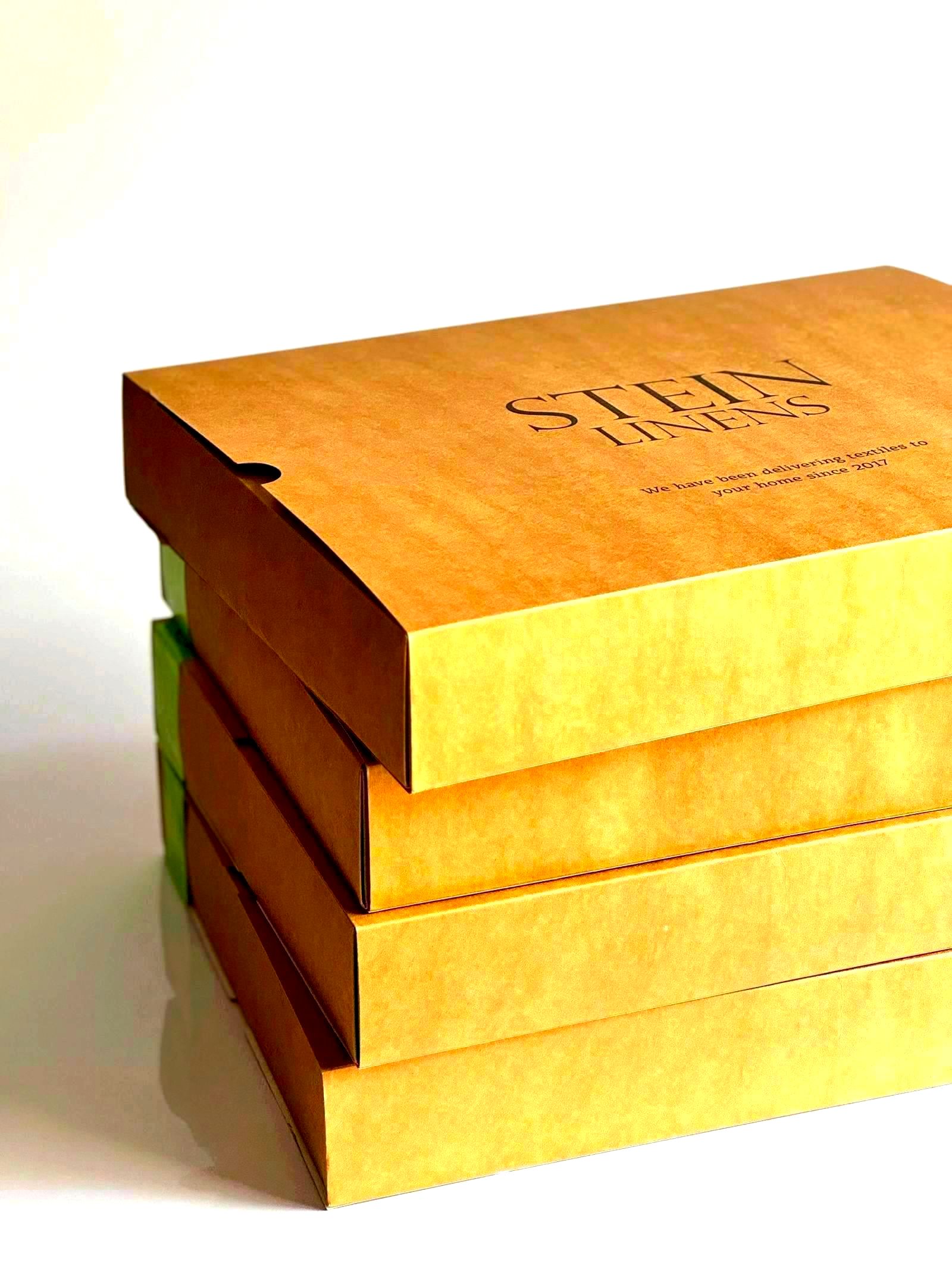 Stack of eco-friendly branded packaging boxes with sustainability marketing claims