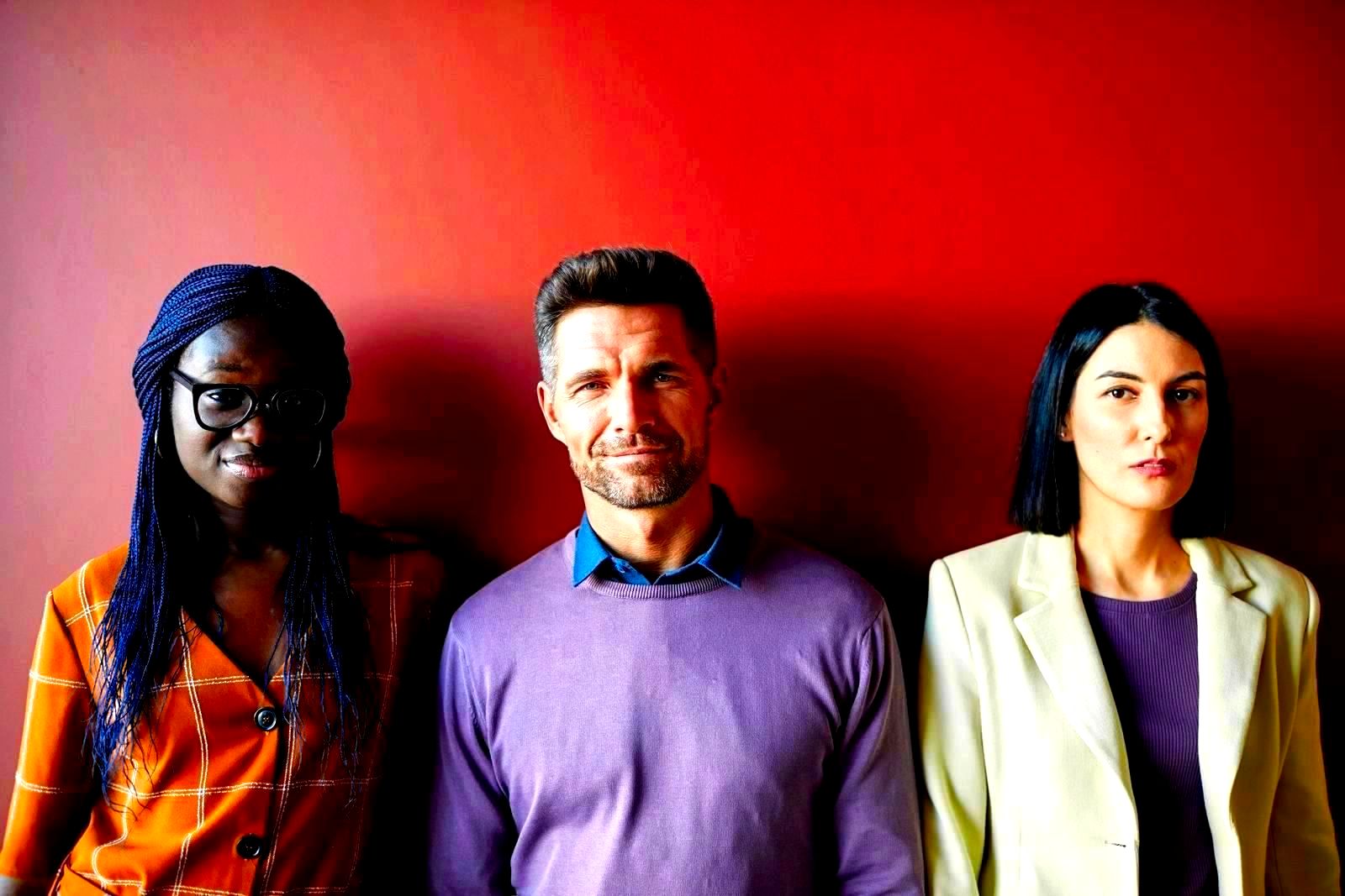 Diverse group of professionals standing together against a red background