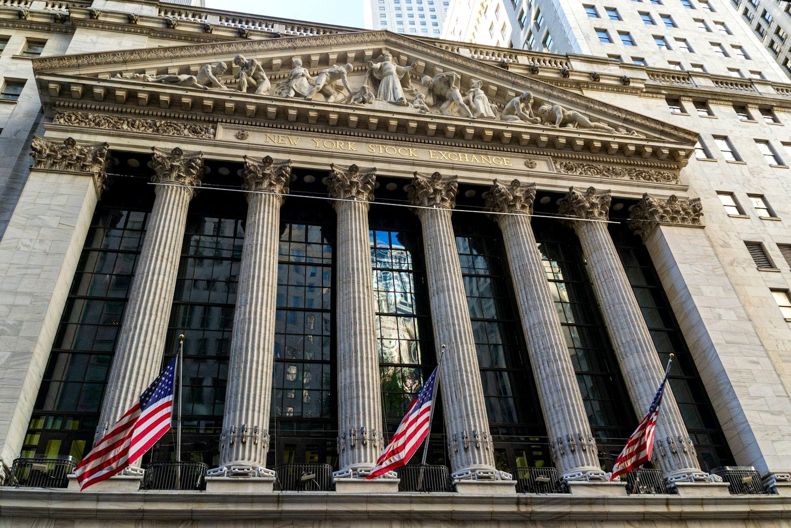 The columned Broad Street facade of the New York Stock Exchange with three American flags