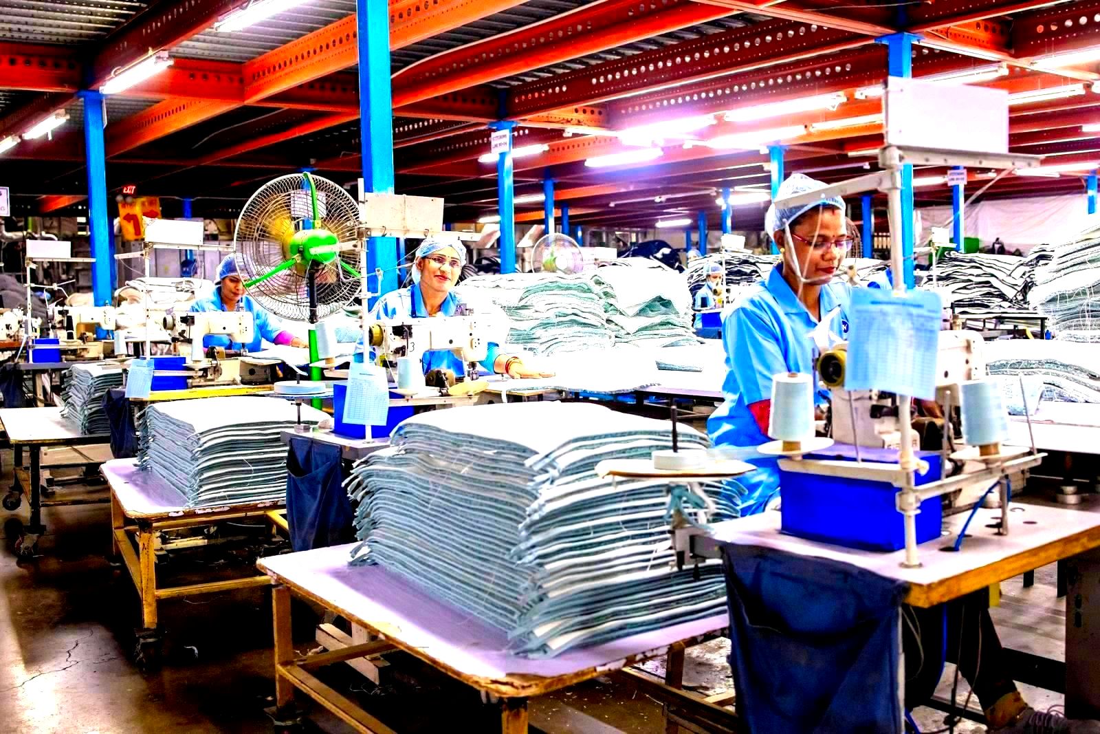 Workers at sewing machines in a textile garment factory floor