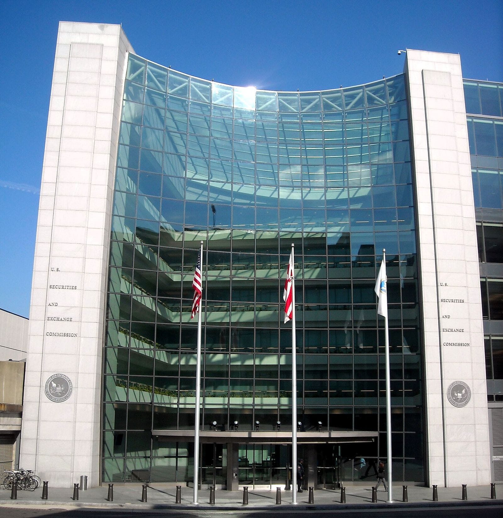 Glass-fronted headquarters of the U.S. Securities and Exchange Commission in Washington with three flagpoles at the entrance